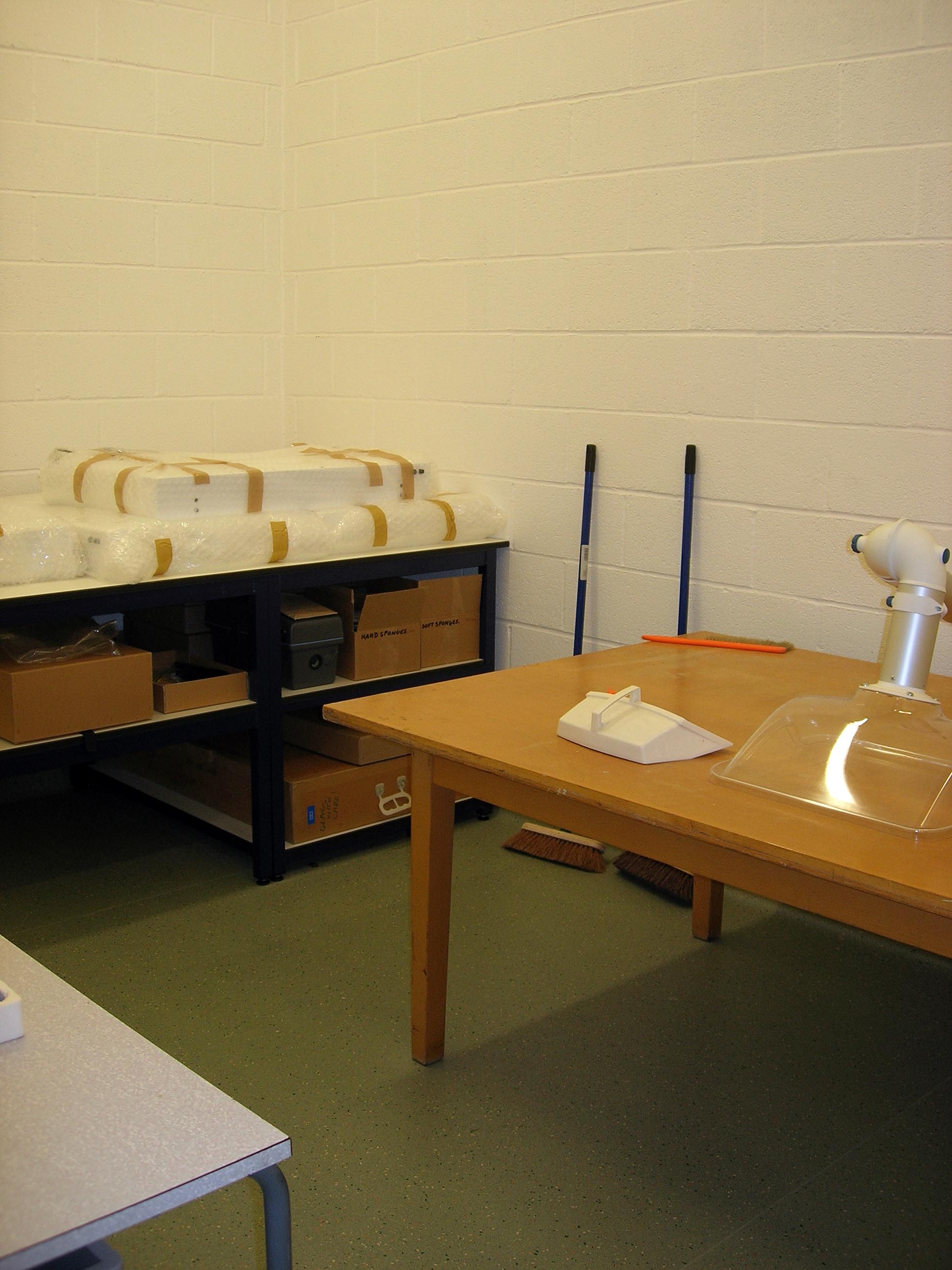 A room with white walls and a green floor. There are several tables in the room, one table has a clear dome with tubing attached on it. A room with white walls and a green floor. There are several tables in the room, one table has a clear dome with tubing attached on it.