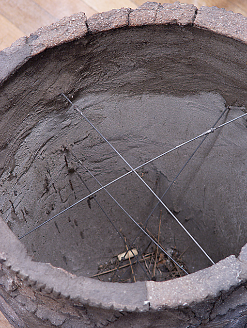 The inside of a pot viewed from above. There are bicycle spokes bracing the sides of the pot. The inside of a pot viewed from above. There are bicycle spokes bracing the sides of the pot.