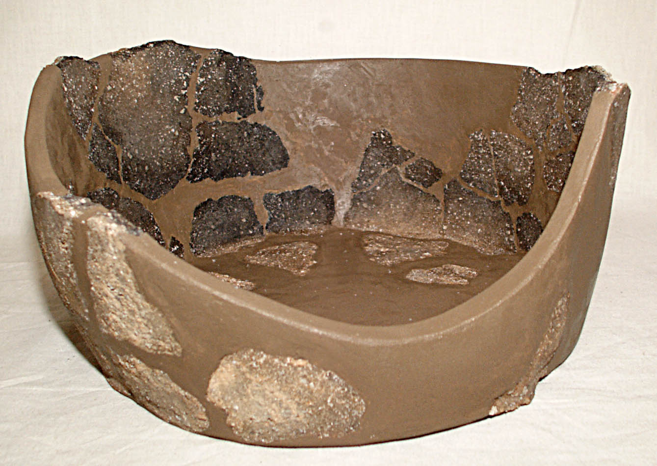 The base section of a pot with the gap fills painted brown. The rest of the pot is missing The base section of a pot with the gap fills painted brown. The rest of the pot is missing