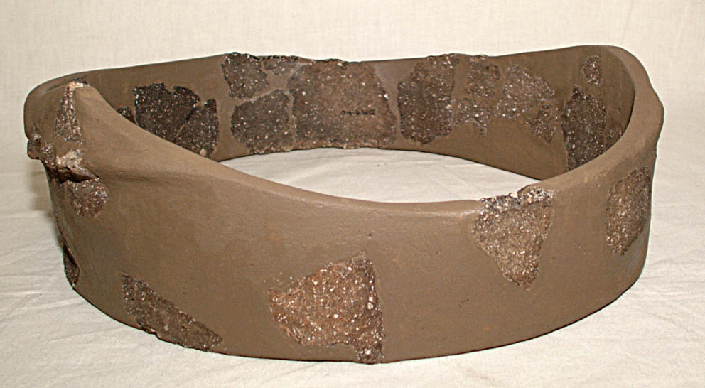 The reconstructed rim of a pot with the gap fills painted brown. The rest of the pot is missing The reconstructed rim of a pot with the gap fills painted brown. The rest of the pot is missing