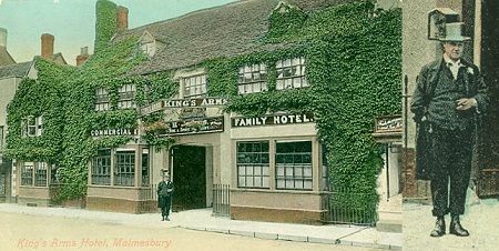 colourised postcard showing formally suited man standing outside entrance to ivy-clad building with sign of King's Arms