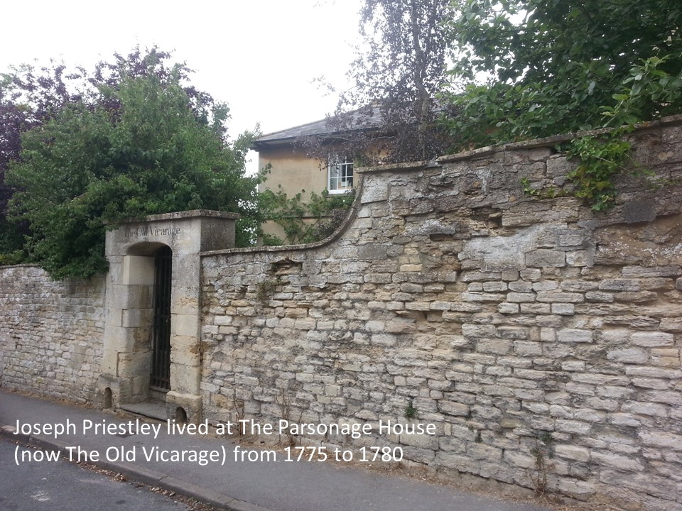 Roof and top corner of Georgian building with sash window above high stone wall with a grand arched stone gateway with 