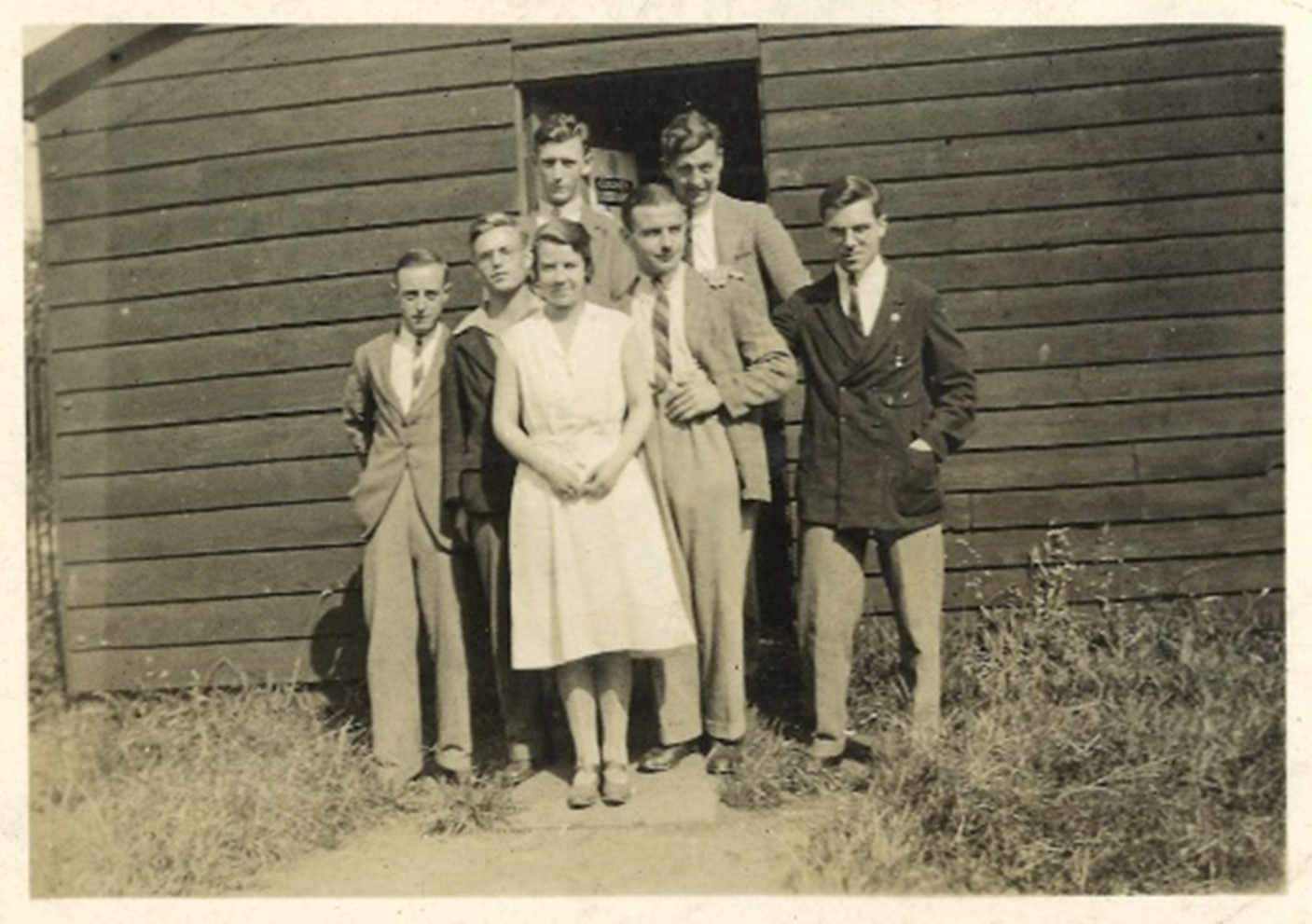 A group of people stood in front of an entrance to a wooden building