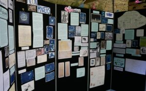 A set of five black exhibition boards containing text, photographs and artwork from the Sounds of the South West project