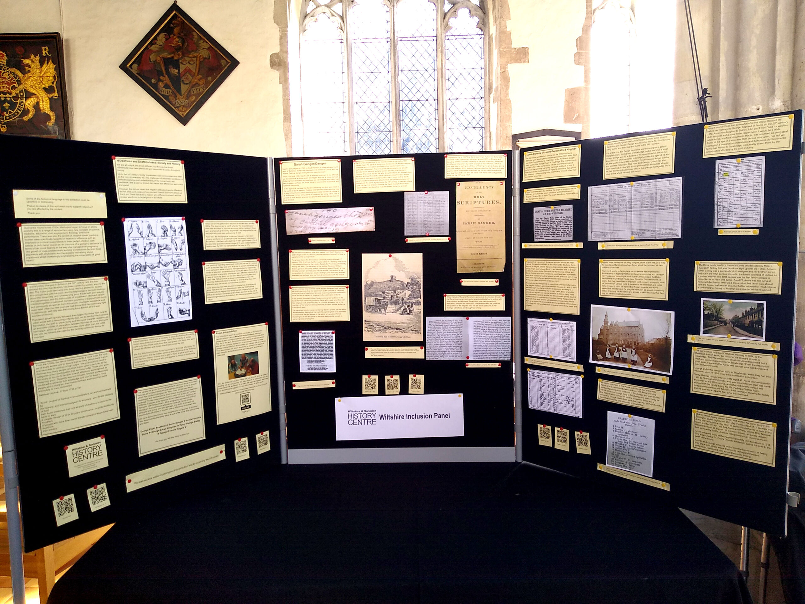 Three exhibition boards displaying beige paper captions and images